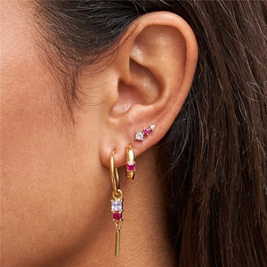 Detail of gold flower earrings set with red and white zircons on a female model