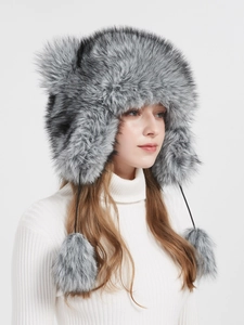 Detail view of plush silver grey faux fur winter trapper hat with furry pom-pom ties