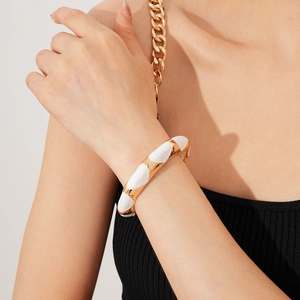 Detail of a French vintage oval open bangle with white enamel and golden metal finish