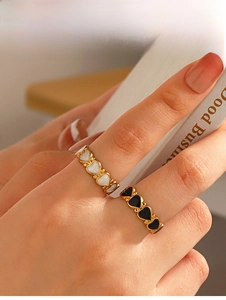 Detail of gold-plated open rings with black and white enamel heart shapes on hand