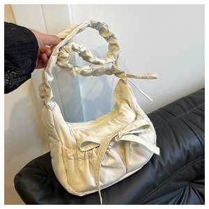 Detail of off-white puffer shoulder bag featuring pleated texture and cute ribbon bow