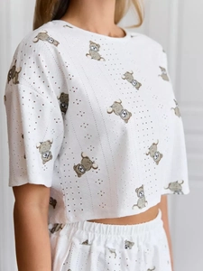 Detail of white eyelet fabric pajamas with cute cartoon bear print and crop top texture