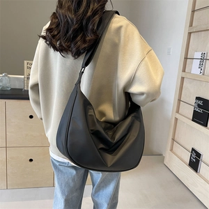 Black crescent dumpling bag worn by a model in a minimalist home setting, large capacity