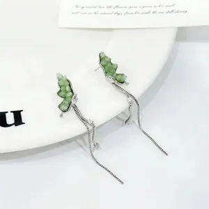 Detail of silver butterfly tassel earrings with light green stones on a white ceramic plate