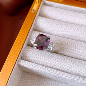 Macro view of cushion-cut purple zircon ring with triangle side stones in a jewelry box