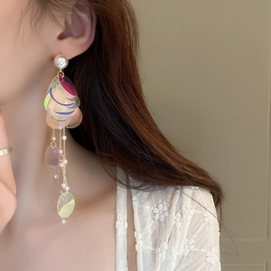 Macro shot of long fringe earrings featuring iridescent sequins and dainty faux pearls