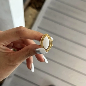 Close-up of gold stainless steel ring with white marquise stone worn on a finger
