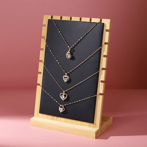 Bamboo necklace display stand with black leather panel and gold heart pendants