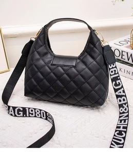 Detail of black quilted leather handbag featuring a wide patterned strap and S-logo
