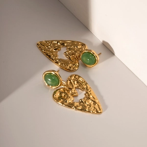 Dettaglio di orecchini vintage a cuore in oro martellato con pietre verdi