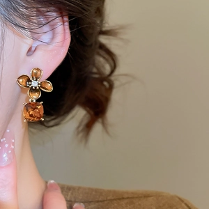 Close-up of vintage flower earrings with amber crystals and gold plating on model