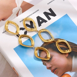 Close-up of geometric 18K gold plated stainless steel triple rhombus earrings on magazine