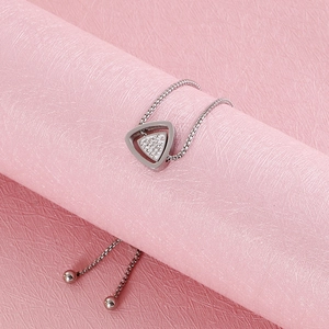 Détail d'un bracelet en acier titane argenté avec pendentif triangle et zircons brillants
