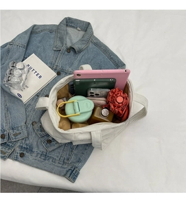 Spacious interior of white corduroy tote bag showing tablets, umbrella, and water bottle