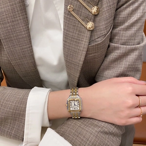 Detail einer eleganten quadratischen Quarzuhr mit Goldband und römischen Ziffern