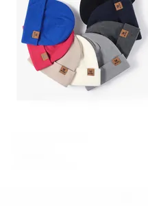 Close-up of assorted colorful knitted beanies featuring premium leather brand patches