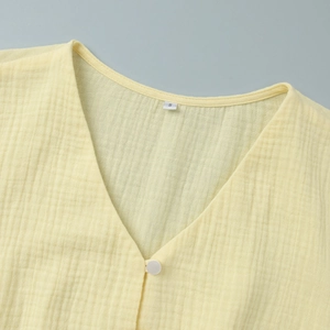 Close-up of V-neckline on yellow cotton gauze dress with texture and size label
