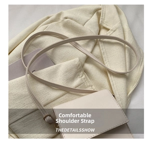 Detail view of the adjustable leather shoulder strap and fine stitching on the beige square bag