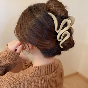 Macro shot of minimalist beige hair claw clip styled on a woman's twisted bun hairstyle