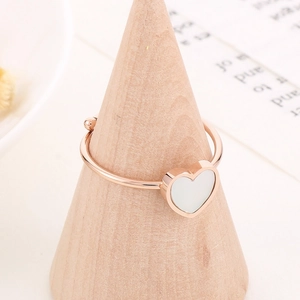 Detail of adjustable rose gold heart ring with white inlay on a wooden stand