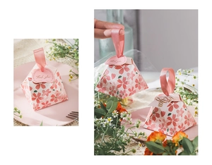 Close-up of cherry blossom triangular candy box with pink ribbon for wedding favors