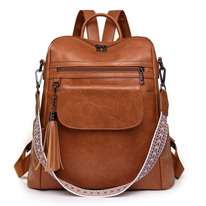 Detail of brown PU leather backpack featuring fringe charm and colorful woven shoulder strap
