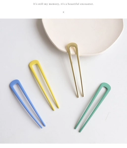 Close-up of matte metal U-shaped hairpins in pastel blue, yellow, and mint green