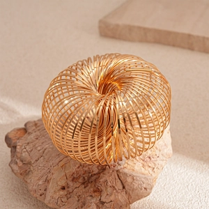 Detail of a geometric golden spring bracelet displayed on a natural stone surface