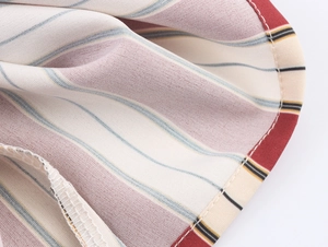 Vue macro du tissu sergé rayé et des coutures blanches soignées sur le chemisier