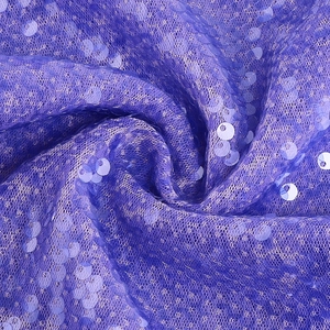 Macro scatto di tessuto a rete con paillettes viola con riflessi di luce e dettagli