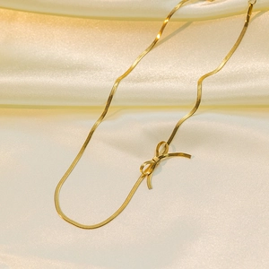 Elegant 18K gold plated bow choker necklace on silk fabric with flat snake chain