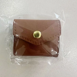 Detailed view of a brown leather jewelry pouch with gold snap button in protective packaging
