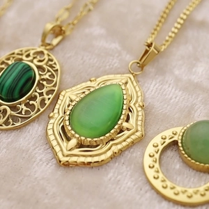 Gold plated oval natural stone pendant necklaces with vintage engravings on beige velvet
