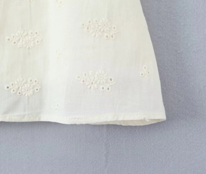 Detailed macro view of white floral embroidery lace fabric with delicate cutout patterns