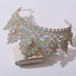 Detail of baroque gold bridal crown featuring light blue crystals on a display stand