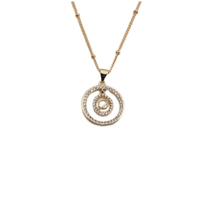 Détail d'un collier doré avec pendentif double anneau et motif de planète scintillante