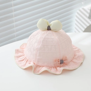 Détail d'un chapeau de soleil rose en dentelle pour bébé avec nœud crème et bord à volants