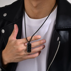 Detail of black stainless steel rectangle pendant with industrial tire pattern for men