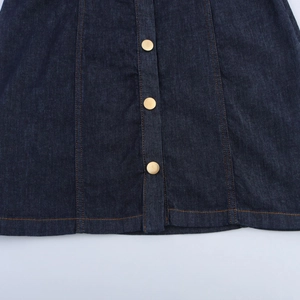 Détail de la robe en jean vintage avec boutons dorés et coutures contrastées orange vif