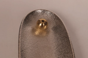 Macro shot of silver textured alloy base with brass incense holder ball detail