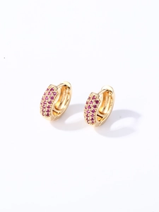 Détail de boucles d'oreilles huggies dorées serties de zircons violets et rubis