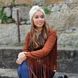 Detail of bohemian cream knit turban hat with twist knot design worn in outdoor setting