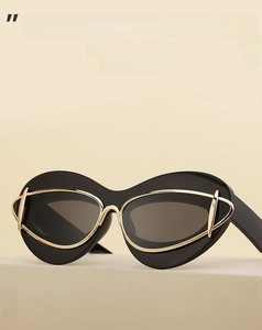 Close-up of futuristic cat eye sunglasses with black frame and golden metal accents