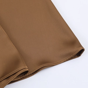 Detailed close-up showing the hem stitching and silky satin texture of a brown skirt