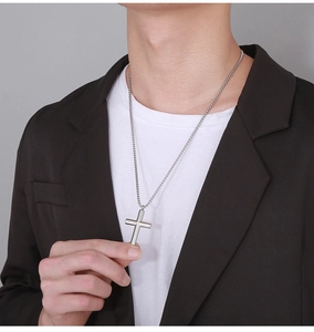 Close-up of polished silver stainless steel cross pendant on a minimalist chain for men