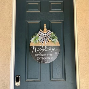 Funny welcome door sign with faux greenery and black and white checkered bow on blue door