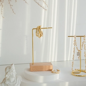 Minimalist gold jewelry display stand set with wooden base and natural shadow detail