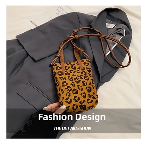 Detail of leopard print mini crossbody bag with brown straps on a blue blazer