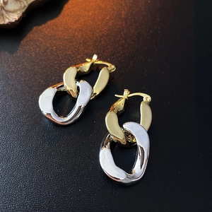 Close-up of interlocking two-tone gold and silver chain link earrings on black leather