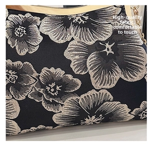 Detailed macro view of black satin fabric with intricate floral embroidery and gold metal hardware
